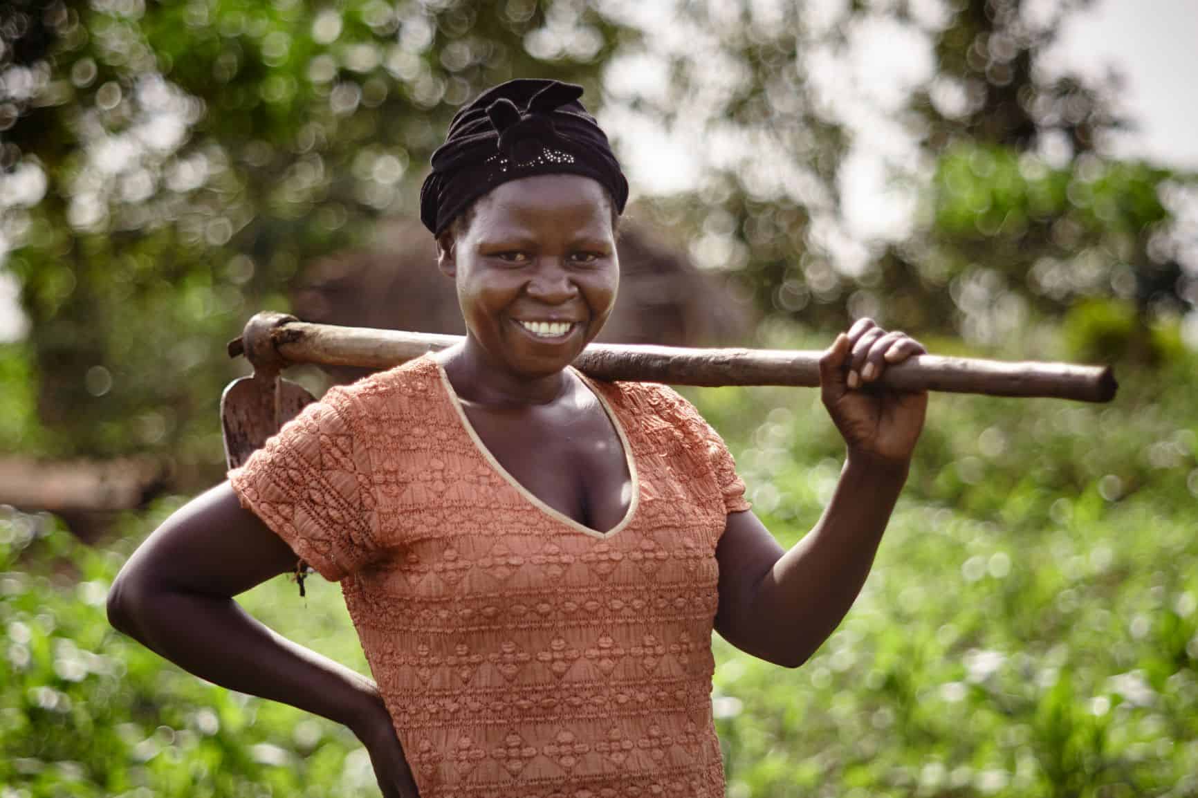 Woman in western Uganda holds a farm tool over her shoulder