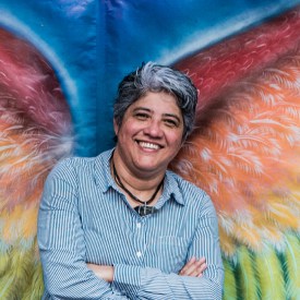 Leader of Cattrachas, which aims to prevent violence against women, stands in front of a rainbow wing artwork