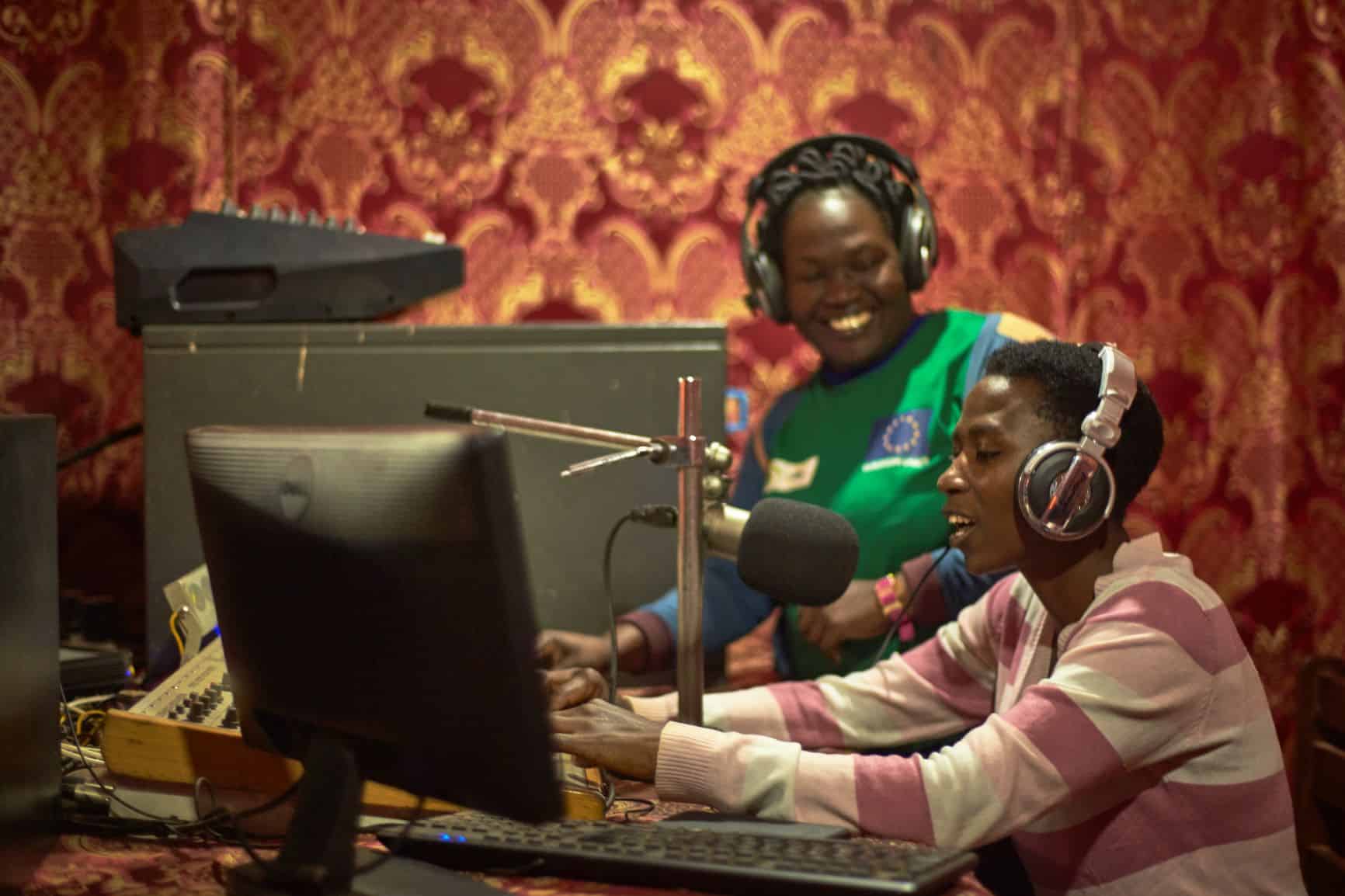 two women in Uganda smile as they produce a community radio episode