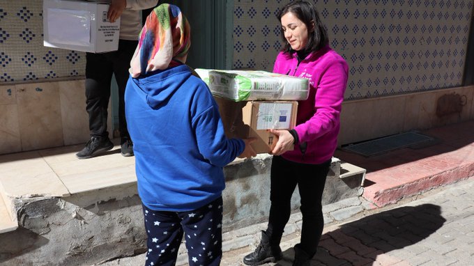 In Turkey, a female activist hands another woman a box of supplies headed to earthquake survivors.