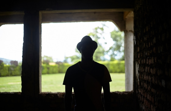 Silhouette of a LGBTQ+ man in Uganda wearing a hat and facing the camera