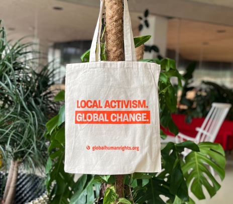 Tote bag hanging from a plant reading Local Activism, Global Change.