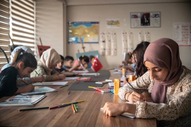 Girls, some of which are wearing headscarves, in a Turkish school write in their notebooks.