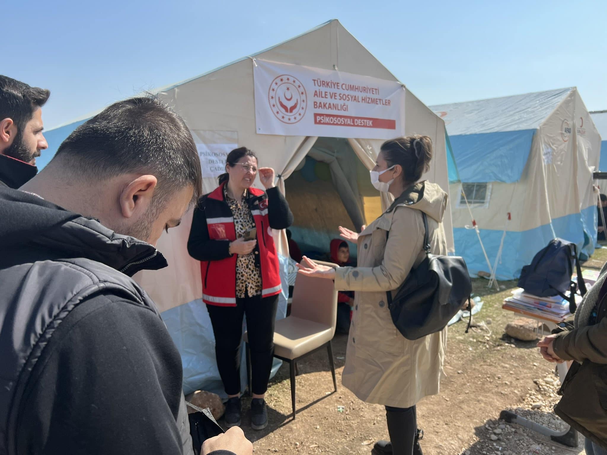 Two woman and two men stand outside a relief tent in conversation