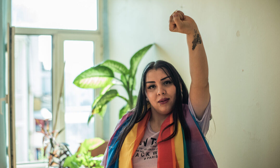 A Fund grantee from the Aman Project in Turkey wears an LGBTQ pride flag and has a raised fist.