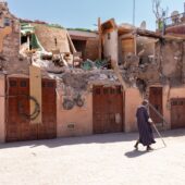 A Man In Dark Clothing With A Walking Stick Passes Homes Damaged By The Earthquake In Morocco