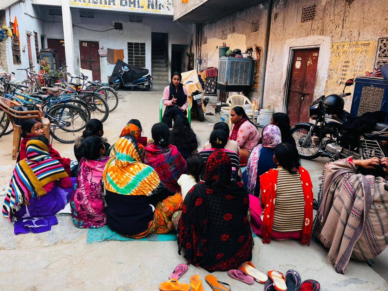 A dozen women sit outside as a women's rights activist speaks