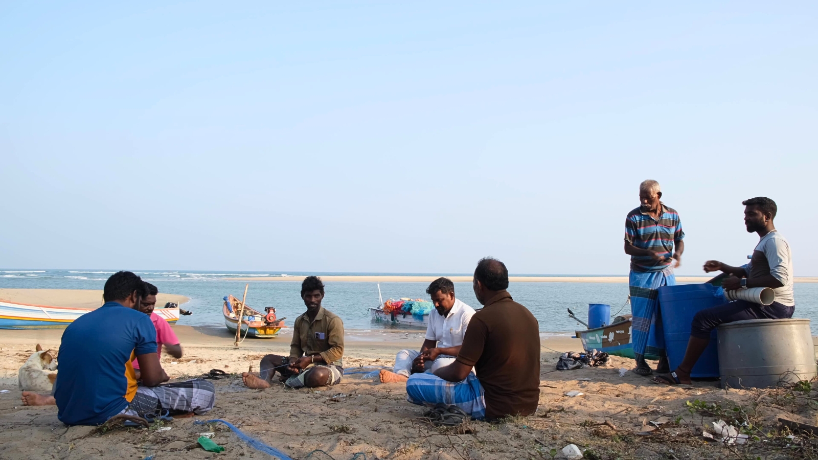 A group of fisherfolk weave and fix nets on a beach in Alamparai, Tamil Nadu, India.