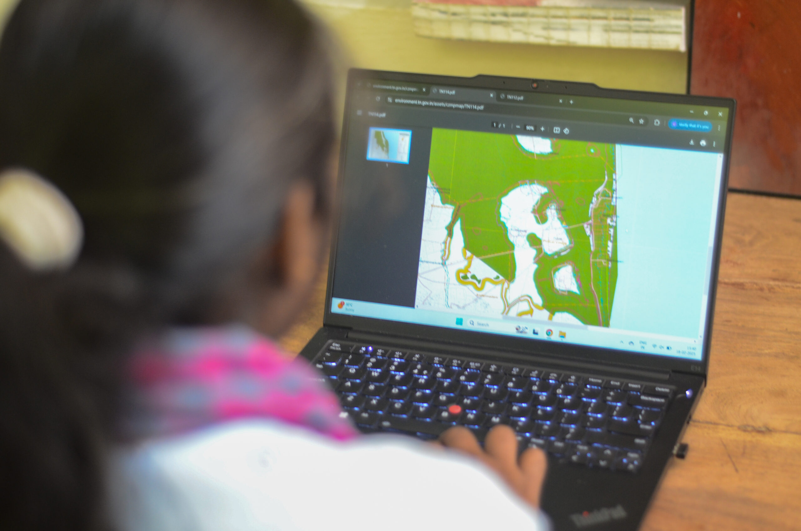 A woman looks at GIS mapping software on a computer.